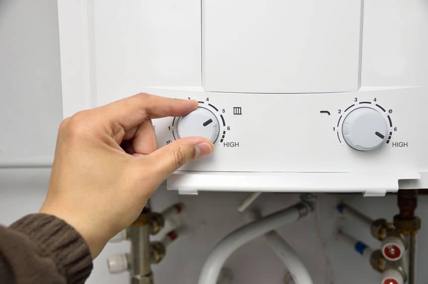 a hand adjusting the settings on a tankless water heater