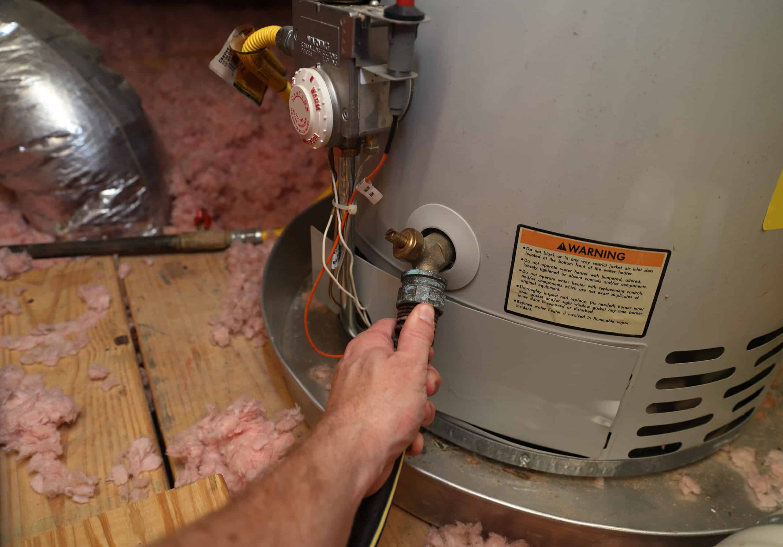 Hand attaches hose to a home water heater to perform maintenance at a home in louisiana