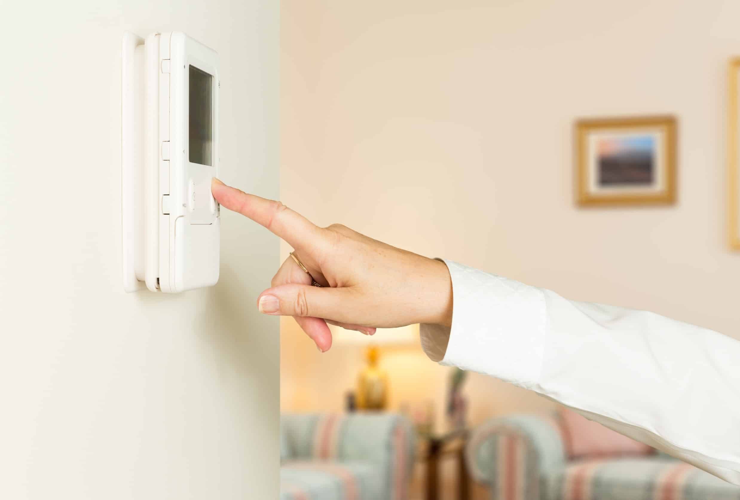 woman adjusting thermostat to heat home
