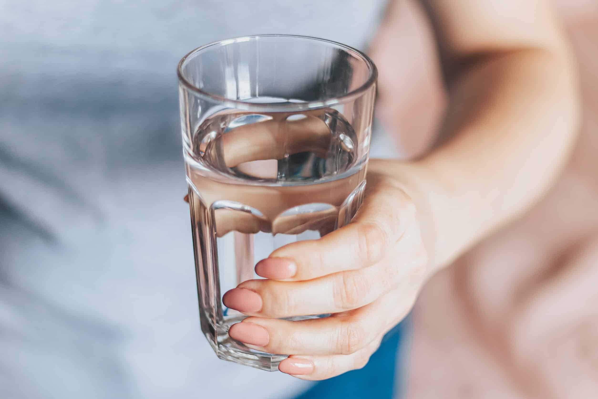 a woman holding a clear glass of water in her left hand