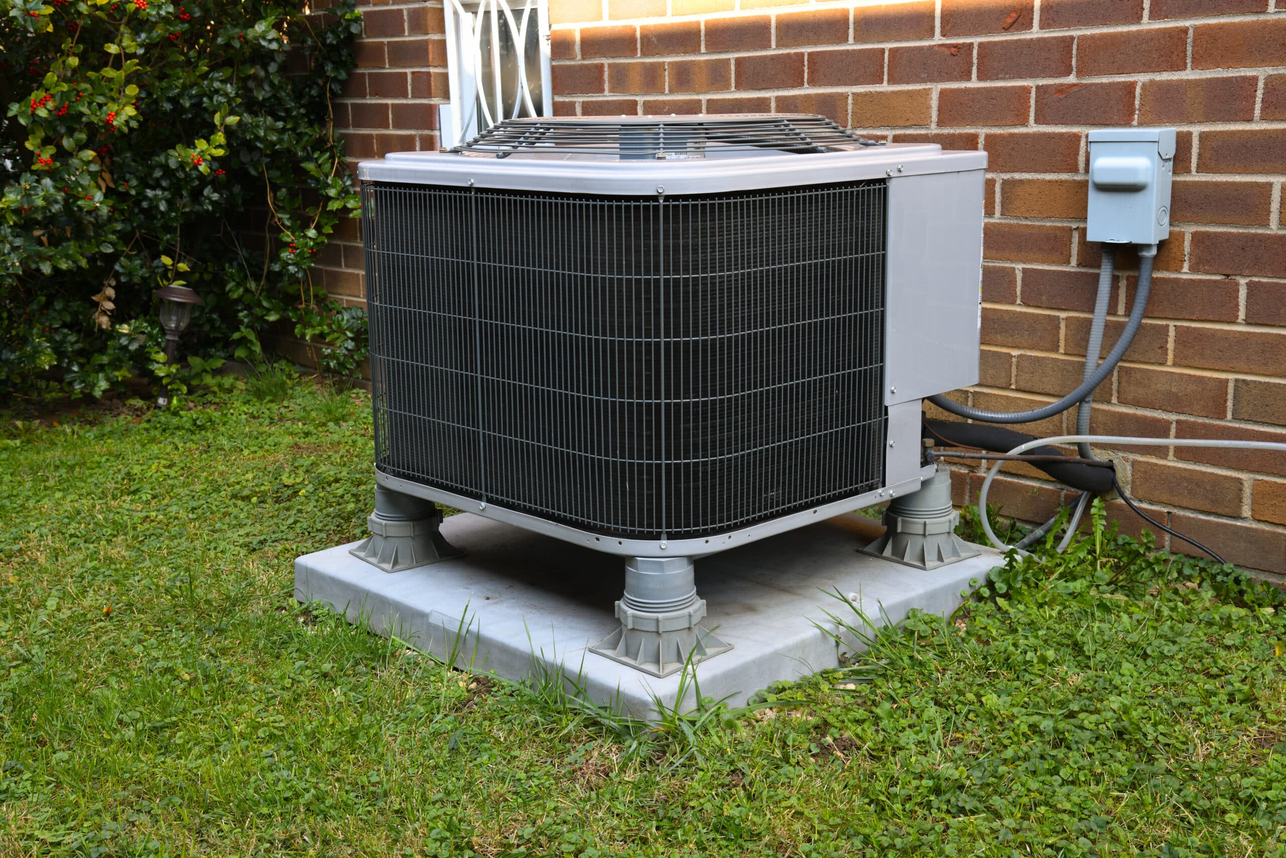 a residential air conditioner next to the side of a brick home