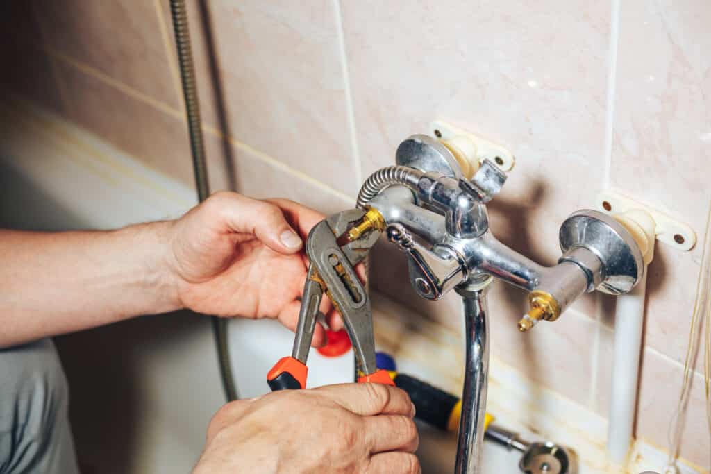 tech repairing a leaking bathroom shower faucet